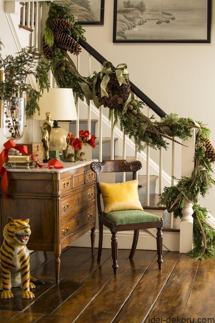 A garland winding up the stair rail is decked with fresh-cut greens, holly branches, giant pinecones, and pheasant feathers.